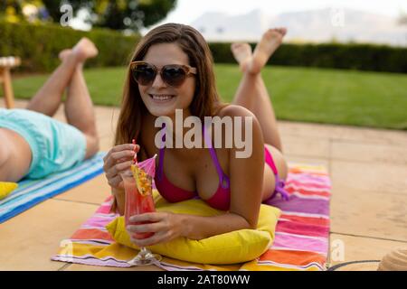 Junge Frau, die sich an einem sonnigen Tag in der Nähe des Schwimmbads erholte Stockfoto