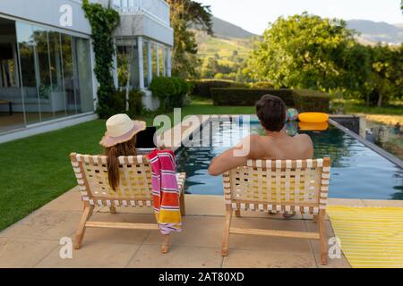 Glückliches junges Paar, das sich in der Nähe des Schwimmbades entspannen kann Stockfoto