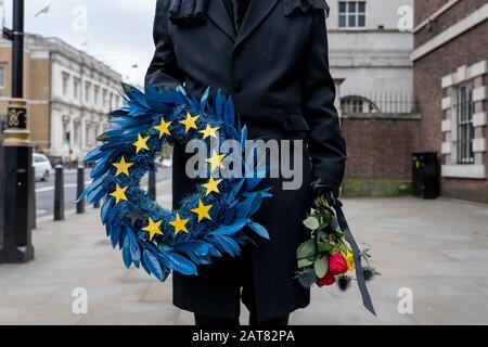 London, Großbritannien. Januar 2020. Ein Mann, der als Unternehmen verkleidet ist, läuft langsam entlang Whitehall, wo er ein Bestattungsrifft der Europäischen Union mit 11 gelben Sternen hält. Stockfoto