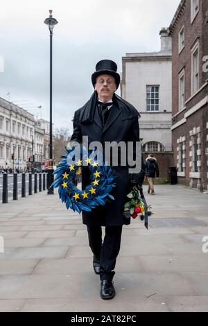 London, Großbritannien. Januar 2020. Ein Mann, der als Unternehmen verkleidet ist, läuft langsam entlang Whitehall, wo er ein Bestattungsrifft der Europäischen Union mit 11 gelben Sternen hält. Stockfoto