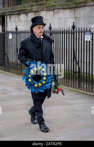 London, Großbritannien. Januar 2020. Ein Mann, der als Unternehmen verkleidet ist, läuft langsam entlang Whitehall, wo er ein Bestattungsrifft der Europäischen Union mit 11 gelben Sternen hält. Stockfoto