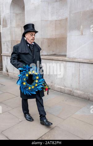 London, Großbritannien. Januar 2020. Ein Mann, der als Unternehmen verkleidet ist, läuft langsam entlang Whitehall, wo er ein Bestattungsrifft der Europäischen Union mit 11 gelben Sternen hält. Stockfoto