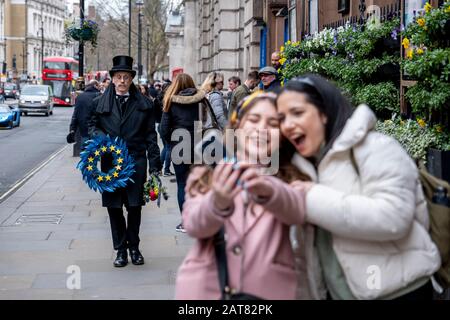 London, Großbritannien. Januar 2020. Zwei junge Mädchen nehmen einen selfie eines Mannes, der als Unterfangen verkleidet ist, der langsam mit EU-Trauerriffen entlang Whitehall läuft. Stockfoto