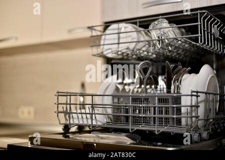 Ein Geschirrspüler mit Geschirr im Küchenschrank eröffnete eine Winkelansicht mit perspektivischer und nahezu vollständiger Unschärfe. Stockfoto