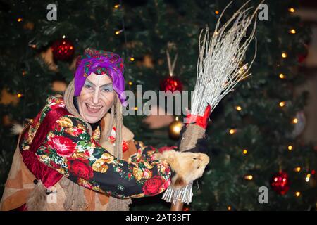 Baba Yaga mit einem Besen auf dem Hintergrund des Weihnachtsbaums. Stockfoto