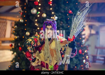 Baba Yaga mit einem Besen auf dem Hintergrund des Weihnachtsbaums. Stockfoto