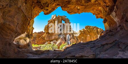 Mann vor einer Höhle mit bizarrer Felsformation im Hintergrund, Stadsaal, Cederberg Wilderness Area, Südafrika Stockfoto