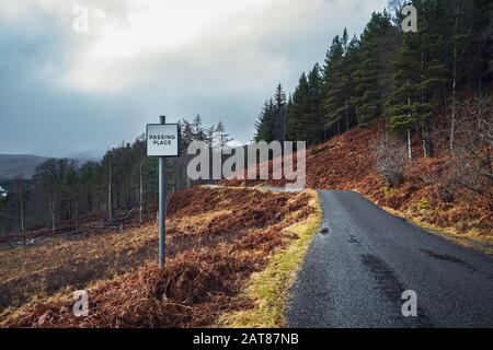 Am Ortsschild auf der einspurigen Straße in Glen Lyon, Schottland, an einem düsteren, nebligen Wintertag vorbei. Stockfoto