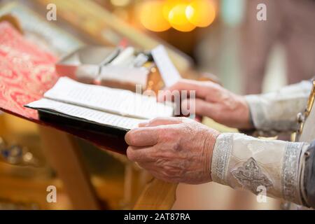 Orthodoxe Religion. Hände des Priesters auf der bibel. Stockfoto