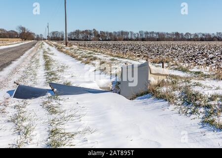 Alter Stuhl und Holzmüll im verschneiten Graben entlang der Landstraße. Begriff des Litterns, der Verschmutzung und des Flugdumpings Stockfoto