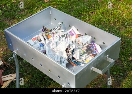 Metallgrill in einem Feld mit Zeitungen nach innen geworfen Stockfoto