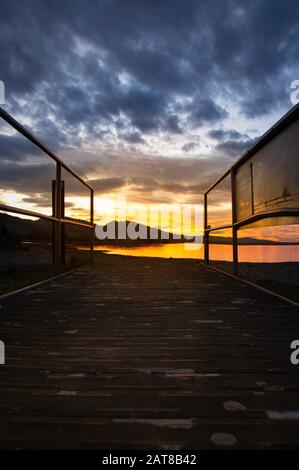 Holzsteg, symmetrisch zum Sonnenuntergang mit hellen und warmen Farben Stockfoto