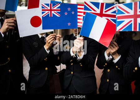 Nahaufnahme von Menschen in Uniform, die kleine Nationalflaggen winken. Stockfoto