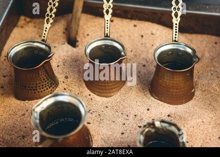 In einem speziellen Turk können Sie traditionellen schwarzen türkischen Kaffee oder Espresso im Sand zubereiten. Stockfoto