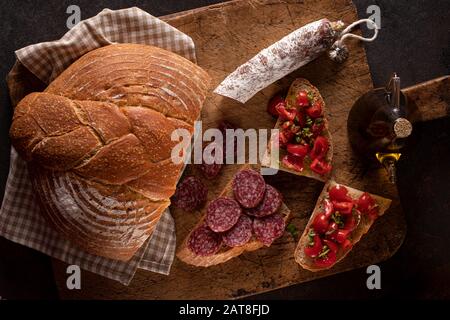 Frisches hausgemachtes Brot mit Salami und Bruschetta mit Tomatenbasil und nativem Olivenöl. Stockfoto