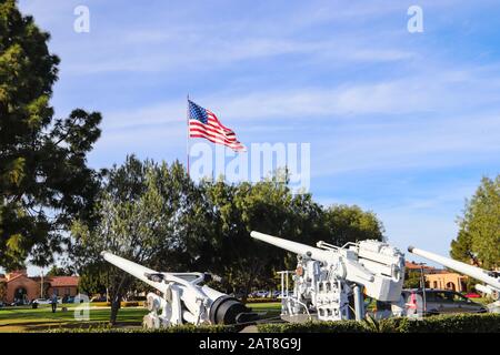 San Diego CA 1-30-2020 Große amerikanische Flagge neben alten ehemaligen Marine-50-Kalibergewehren im Liberty Station Park in San Diego ausgestellt Stockfoto