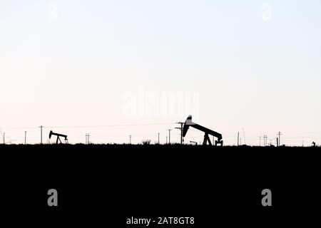 Blick auf die Silhouetten-Ölbohrinsel auf einem Feld Stockfoto