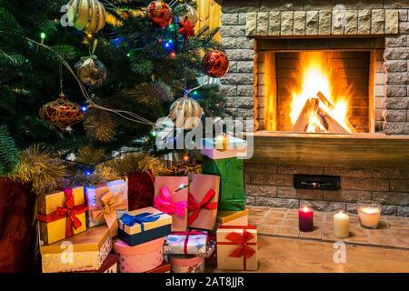 Weihnachtsabend. Weihnachtsbaum und weihnachtsgeschenke und Kerzen vor dem gemütlichen Kamin. Stockfoto