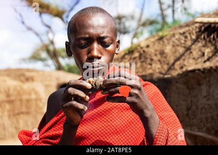 Serengeti, TANSANIA - 7. Januar: Afrikanischer Mann hält einen schwelenden Kuchen in den Händen mit einem roten Herzring. Tansania, Afrika. Stockfoto