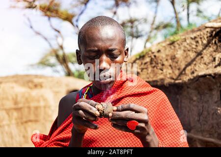 Serengeti, TANSANIA - 7. Januar: Afrikanischer Mann hält einen schwelenden Kuchen in den Händen mit einem roten Herzring. Tansania, Afrika. Stockfoto