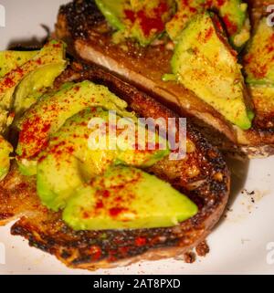 Avocado garniert mit Paprika auf gebuttertem Toast aus nächster Nähe Stockfoto