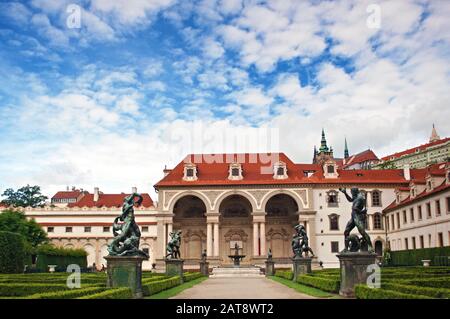 Blick auf den leeren Eingang des Wallensteinpalastes, seine Statuen und seinen Garten, das rote Ziegeldach und den lebhaften blauen Himmel und weiße Wolken am Tag. Prag, Stockfoto