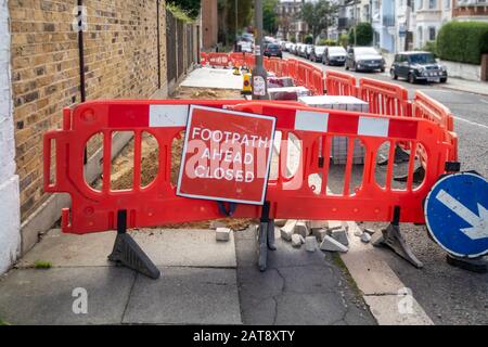 Bauarbeiten zur Verlegung neuer Pflasterstreifen und provisorischer Fußweg schlossen rotes Warnschild auf dem Londoner Bürgersteig Stockfoto