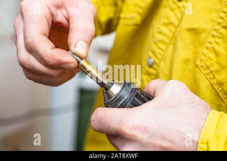 Die Stifthänder montieren eine Metalldüse zum Verdrehen der Schrauben an einem Akkuschrauber. Reparatur zu Hause. Stockfoto