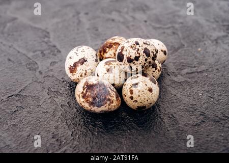 Wachteleier auf schwarzem Hintergrund. Mehrere Wachteleier liegen auf einem schwarzen Stein Hintergrund Stockfoto