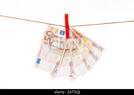 Euro-Banknoten sind mit roten Wäscheklappen an einem Seil auf weißem Grund befestigt Stockfoto