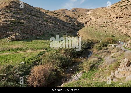 Ein paar Wanderer in der Nähe des Eingangs zum Picknickplatz ein Mabo'a mit wadi qelt nahal prat im Vordergrund und der Judäischen Wüste im Hintergrund Stockfoto