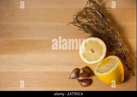 Geschnittene Zitrone, Knoblauch und getrockneter Rosmarin auf einem Holzbrett Stockfoto