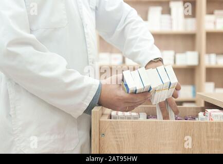 Apotheker hält eine Packung Medikamente in einer Apotheke Stockfoto