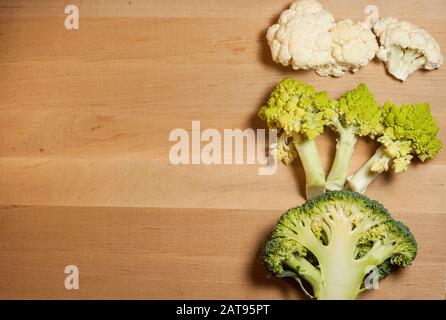 Romanesco, Brokkoli und Blumenkohl liegen hintereinander auf einem Holzbrett Stockfoto