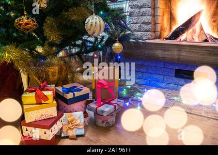 Weihnachtsabend. Weihnachtsbaum und weihnachtsgeschenke und Kerzen vor dem gemütlichen Kamin. Stockfoto