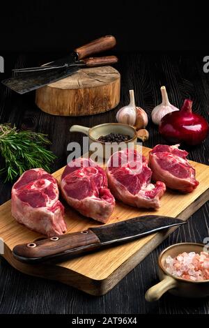 Gehacktes frisches Lammkeulensteak auf Schneidebrett mit Gewürz Stockfoto