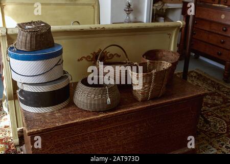 Vintage-Holzbett und -Kofferraum mit Korbkörben in einem Antiquitätengeschäft. Maine, USA Stockfoto