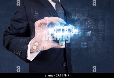 Geschäftsmann, der eine Glühbirne mit JETZT EINSTELLENDER Aufschrift hält, neues Geschäftskonzept Stockfoto