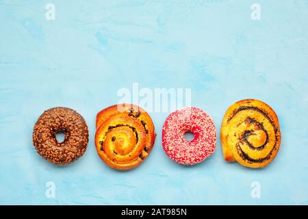 Köstliche Schokoladen-Douglasien und -Brötchen mit Mohnsamen und Rosinen auf einer helltürkisfarbenen Oberfläche. Stockfoto