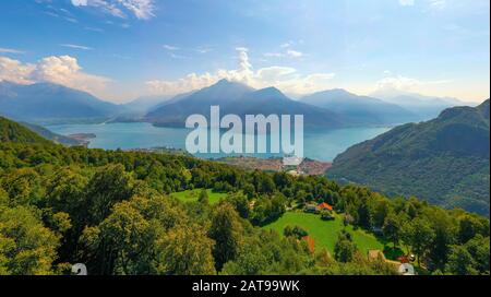 Weitwinkelpanorama des Comer Sees mit Alpengebirge auf Dem Hintergrund und Bäumen im Vordergrund. Postkartenkonzept Für Reisen Stockfoto