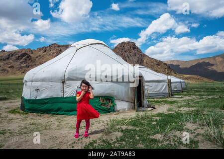 Mongolisches Mädchen vor traditionellen Yurten (mongolische Niger) an einem sonnigen Tag in Bayan-Olgii, West Mongolia. Stockfoto