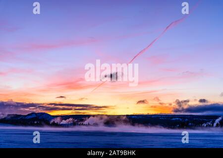 Dampf steigt bei Sonnenuntergang aus Erdwärme. Yellowstone National Park, Wyoming, USA Stockfoto