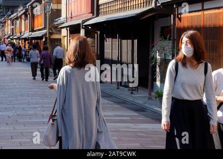 Zwei junge Frauen, eine mit Maske, im Higashi-Chaya-Distrikt ('Eastern Teahouse-Distrikt') von Kanazawa. Stockfoto