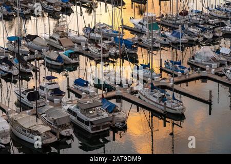 Waikiki, HI - 20. Januar 2020: Untergehende Sonne reflektiert im Wasser durch die Yachten und Boote im Ala Wai Bootshafen Stockfoto