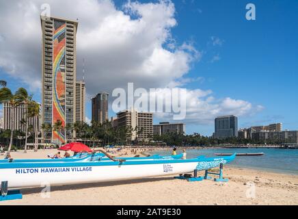 Waikiki, HI - 19. Januar 2020: Traditionelle Kanus vor dem Hilton Rainbow Tower am Waikiki Strand auf Hawaii Stockfoto