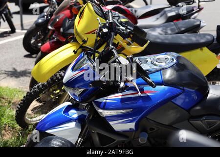 Motorrad: Bunte Fahrräder in Folge, außerhalb der Stadt an einem warmen hellen Tag geparkt. Landschaftsbild. Stockfoto