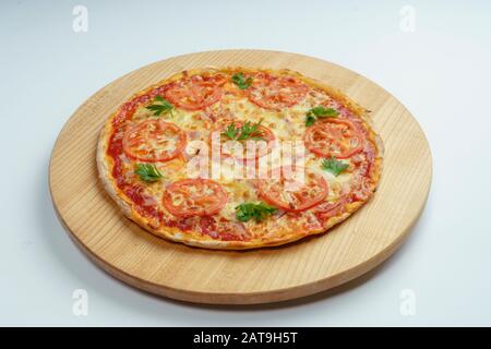 Pizza mit Wurst-, Käse- und Tomatenscheiben, in Ringe geschnitten. Pizza auf einer leichten Holzplatte. Weißer Hintergrund Stockfoto