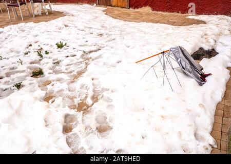 Kaputter Regenschirm, der auf der verschneiten Straße von einem Sturm aus Wind, Regen und Schnee aufgegeben wurde. Stockfoto