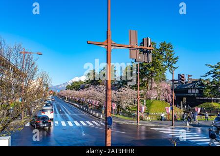 Blick auf die Straße in der Stadt Hirosaki im Frühling sonniger Tag. Kirschblütenmatsuri-Festival, Besucher genießen die Schönheit voller Blüte rosa Sakura-Bäume Blumen. Stockfoto