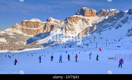 In den Dolden, Italien - 20. Januar 2020: Skifahrer auf den Pisten, am frühen Morgen, mit Sellagruppe im Hintergrund, beleuchtet bei Sonnenaufgang, im Dolmiti Superski dom Stockfoto